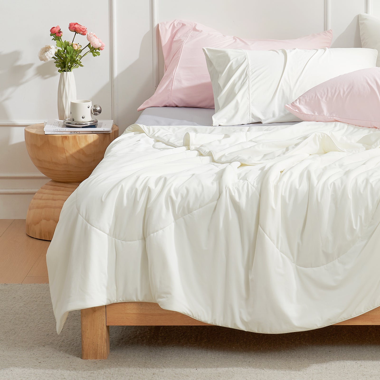 Cream-colored cooling comforter on bed with pink pillows, modern bedroom. #Color_Off White