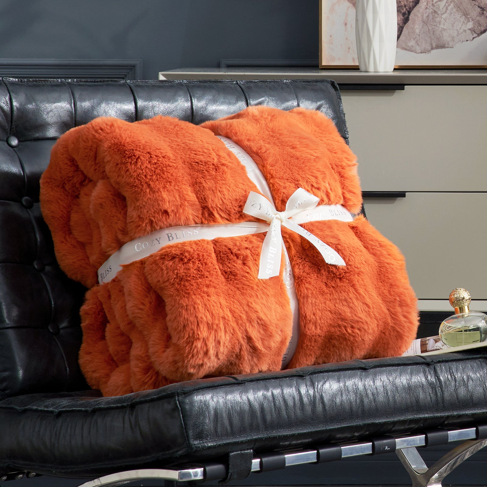Cozy Bliss orange faux fur throw blanket on a black leather chair, a cozy blanket #color_Burnt Orange