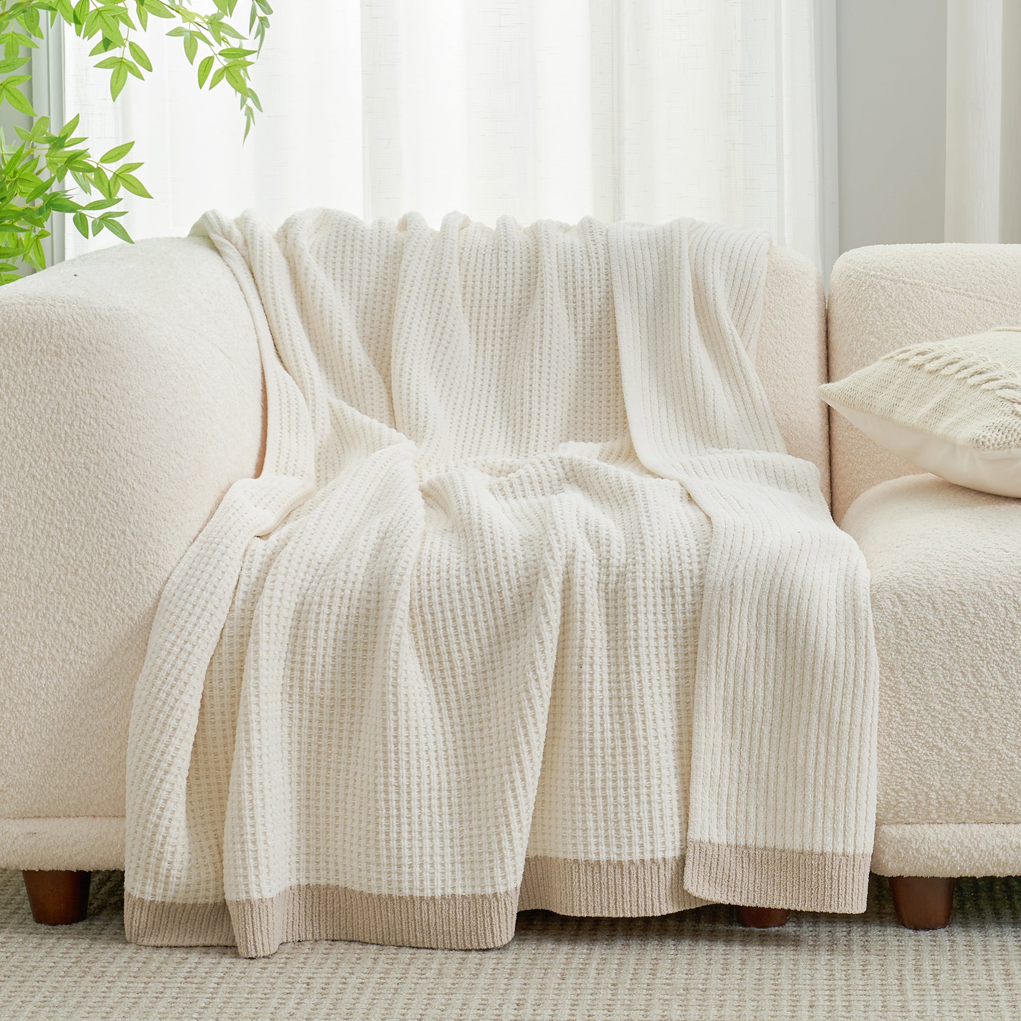 Chenille Waffle Knit Throw Blanket in Ivory draped over a sofa, showcasing its soft neutral tone and texture. #color_Ivory