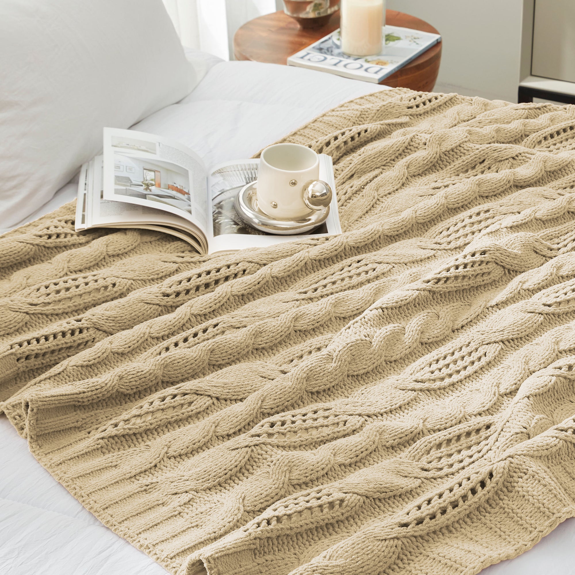 Chenille Cable Knit Throw Blanket in Beige neatly folded on a table, showcasing detailed knit structure and texture. #color_Beige