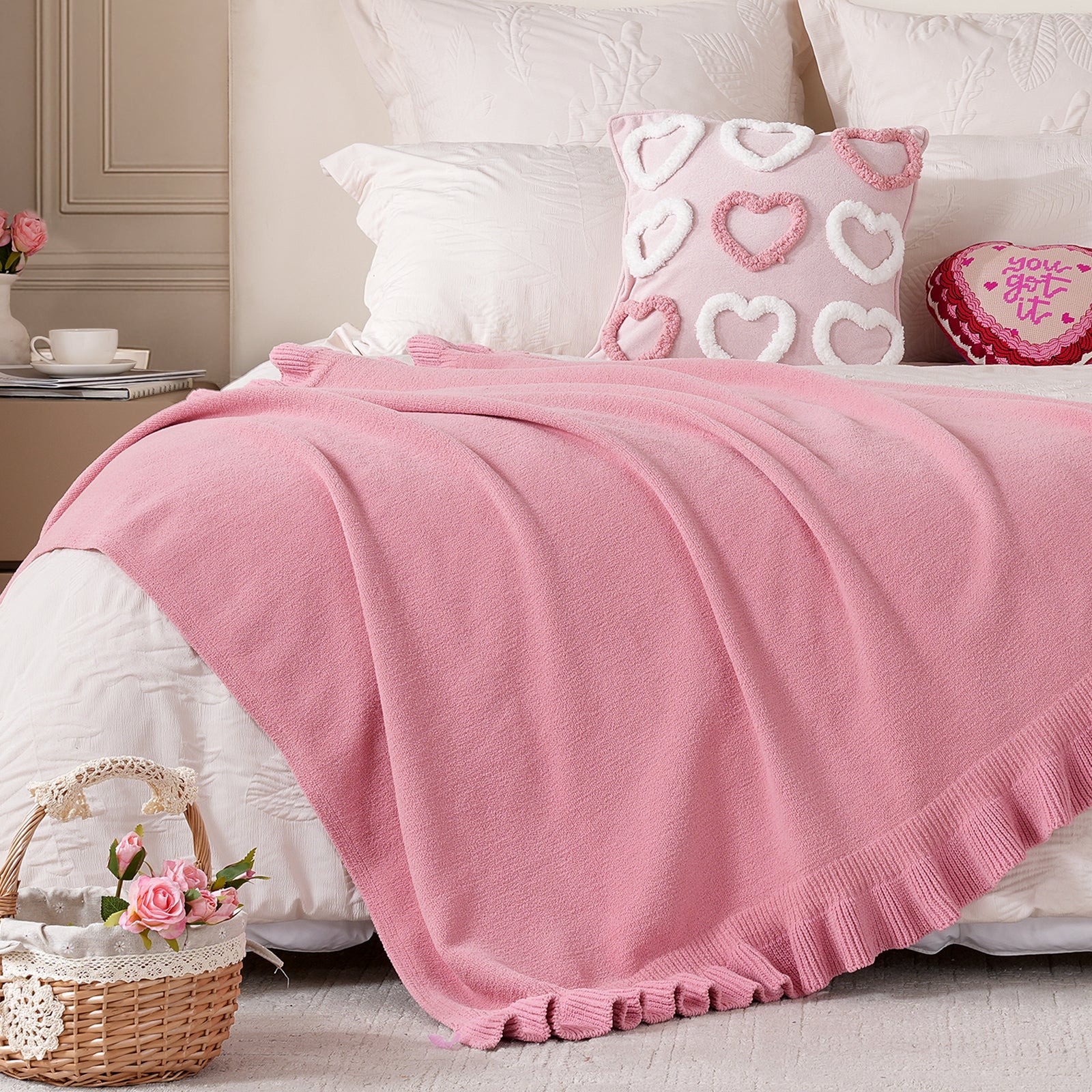 Ruffle Knit Chenille Throw Blanket in Pink styled on a bed with heart decor pillows, creating a soft and romantic bedroom atmosphere. #color_Pink