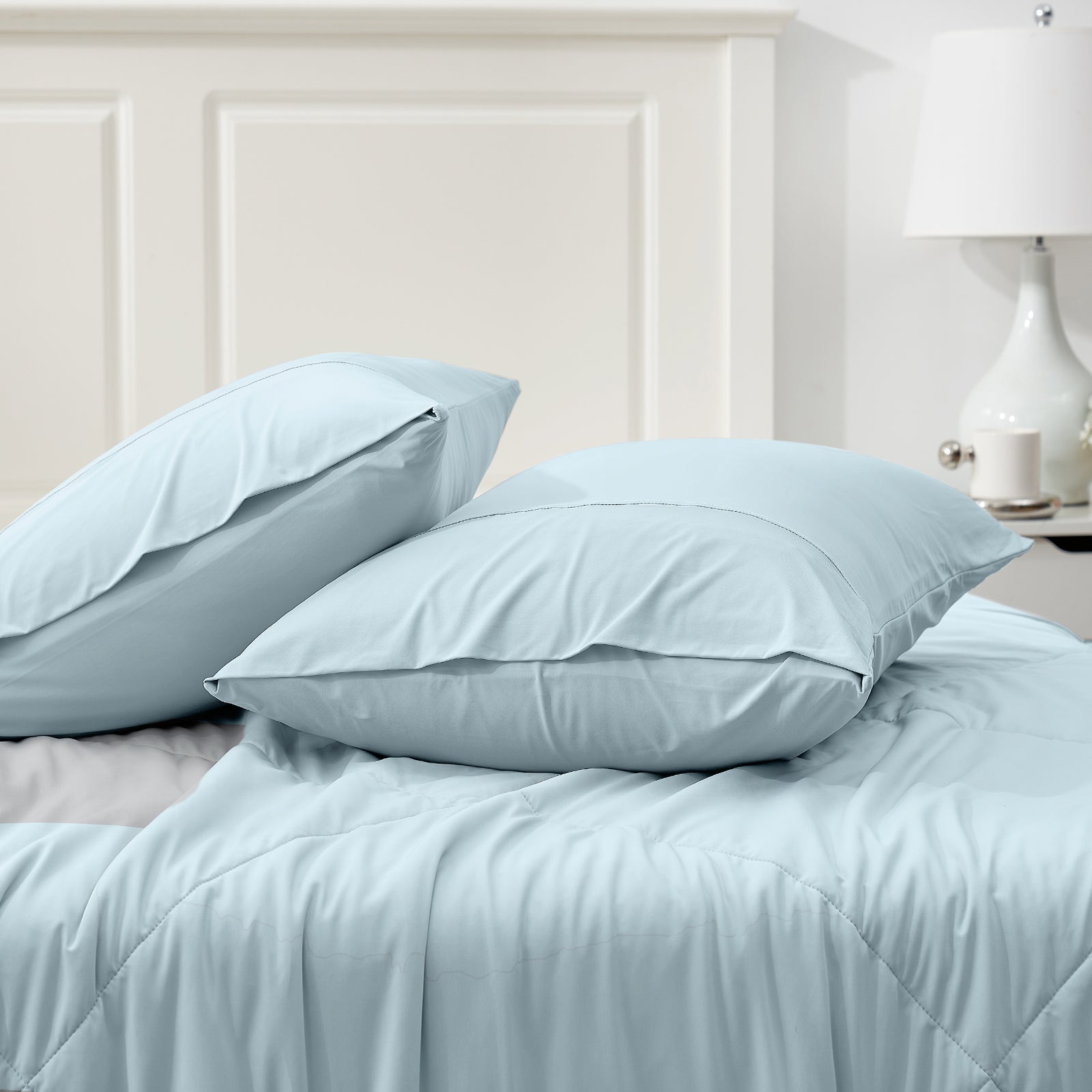 Light blue cooling pillowcases on bed; breathable, soft material for comfortable sleep. #color_Blue
