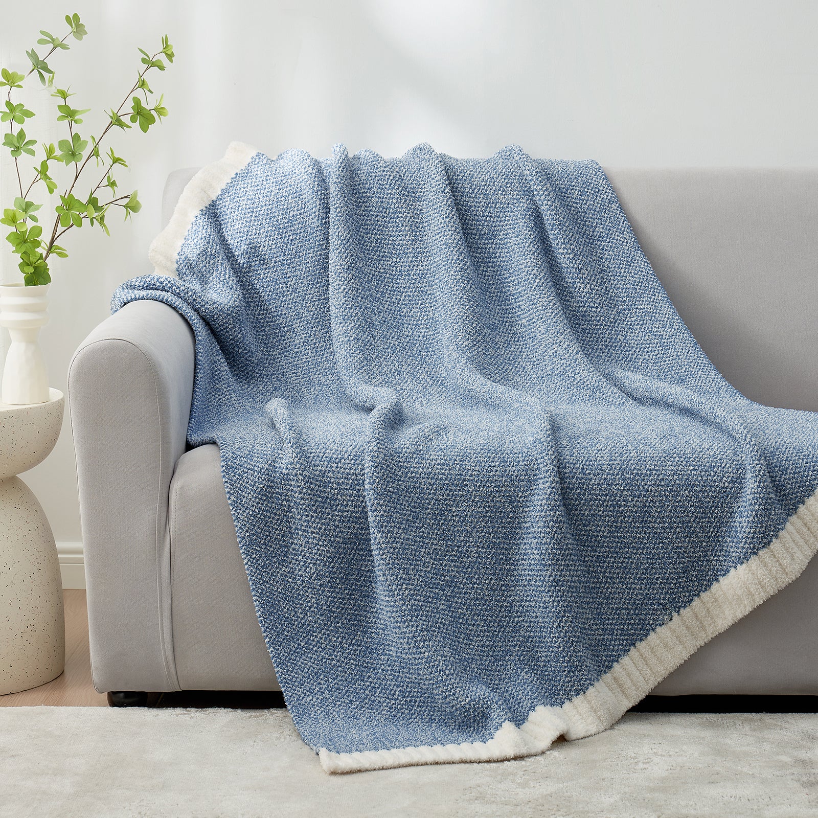 Heather Feather Yarn Throw Blanket in misty blue draped over a sofa, adding warmth, softness and a modern cozy touch to your living room. #Color_Misty Blue