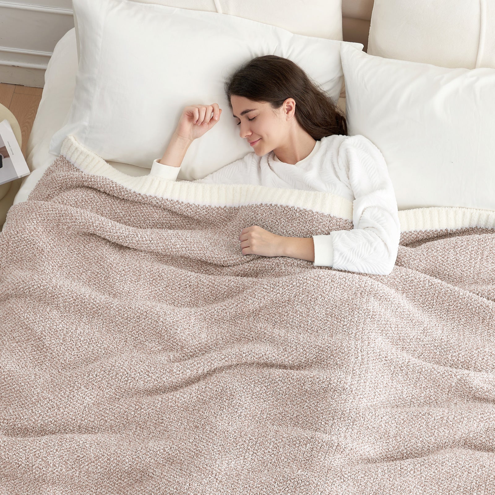 Woman lying on a bed with a Heather Feather Yarn Throw Blanket in Brown, perfect for comfort. #color_Light Brown