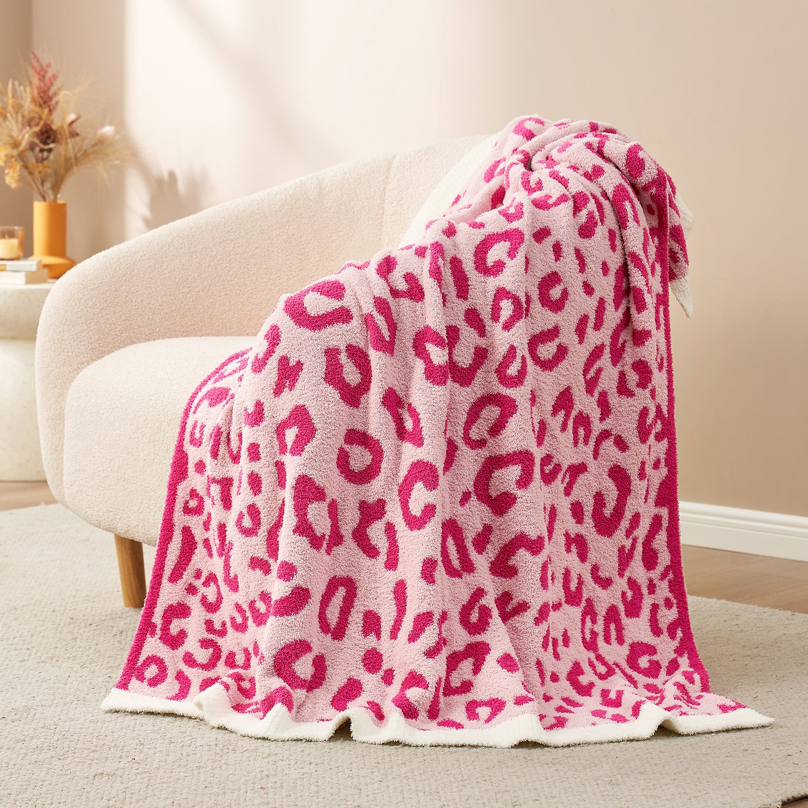 Reversible Leopard Feather Yarn Throw Blanket in Hot Pink draped over an armchair, showcasing its vibrant leopard pattern and soft texture. #color_Hot Pink