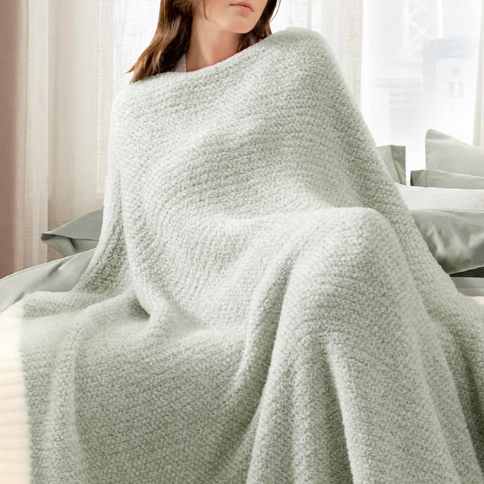Woman wrapped in a Heather Feather Yarn Throw Blanket in Sage Green, relaxing comfortably. #color_Sage Green
