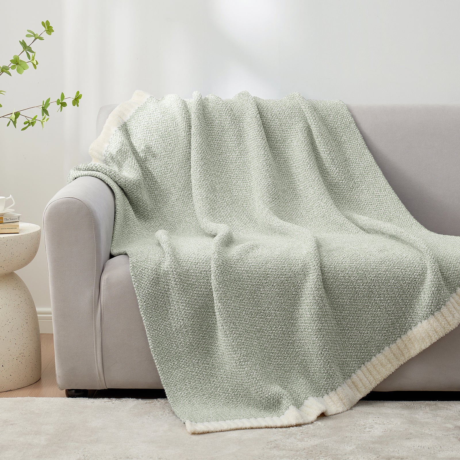 Heather Feather Yarn Throw Blanket in Sage Green draped over a sofa, adding a calm cozy feel. #color_Sage Green