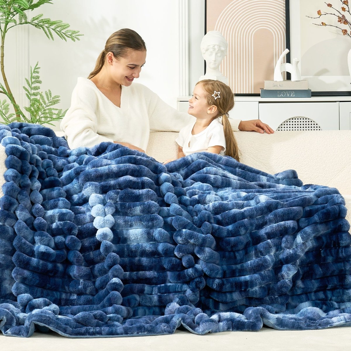 Woman and child sitting on the couch under a blue blanket in a cozy living room setting. #color_Tie-dye Blue