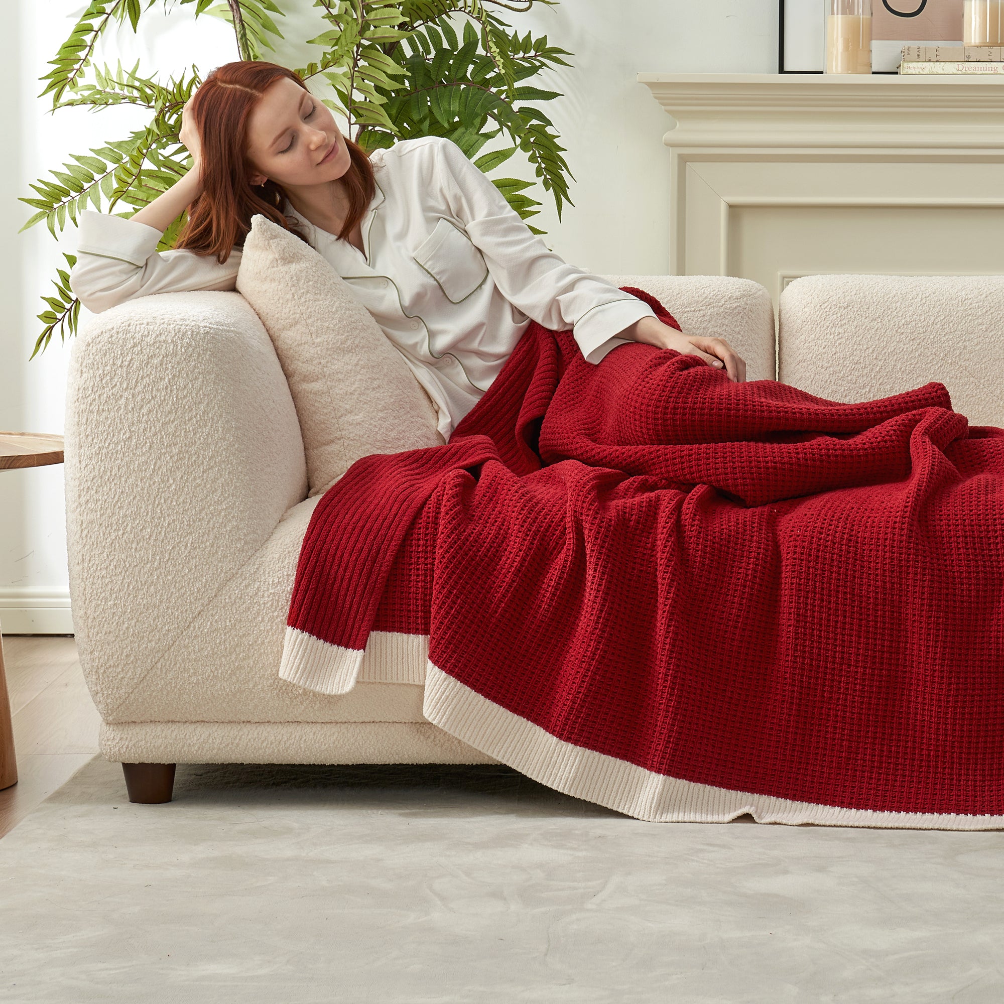 Woman relaxing on a couch with a red blanket in a cozy living room. #color_Red