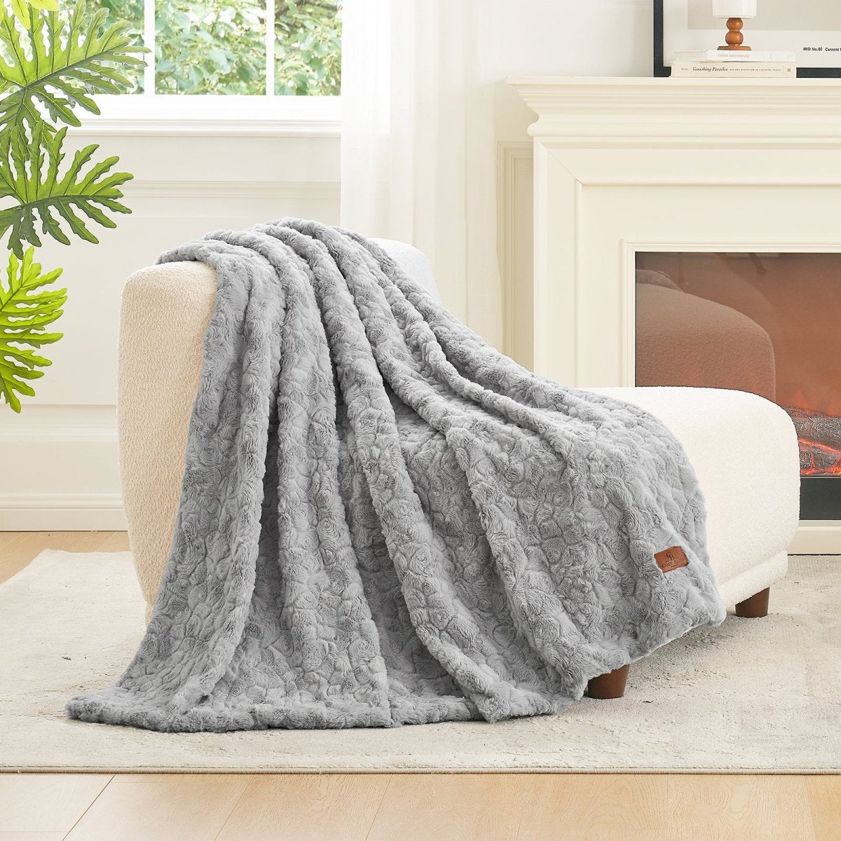 Grey textured blanket draped over a white armchair in a cozy living room. #color_Grey