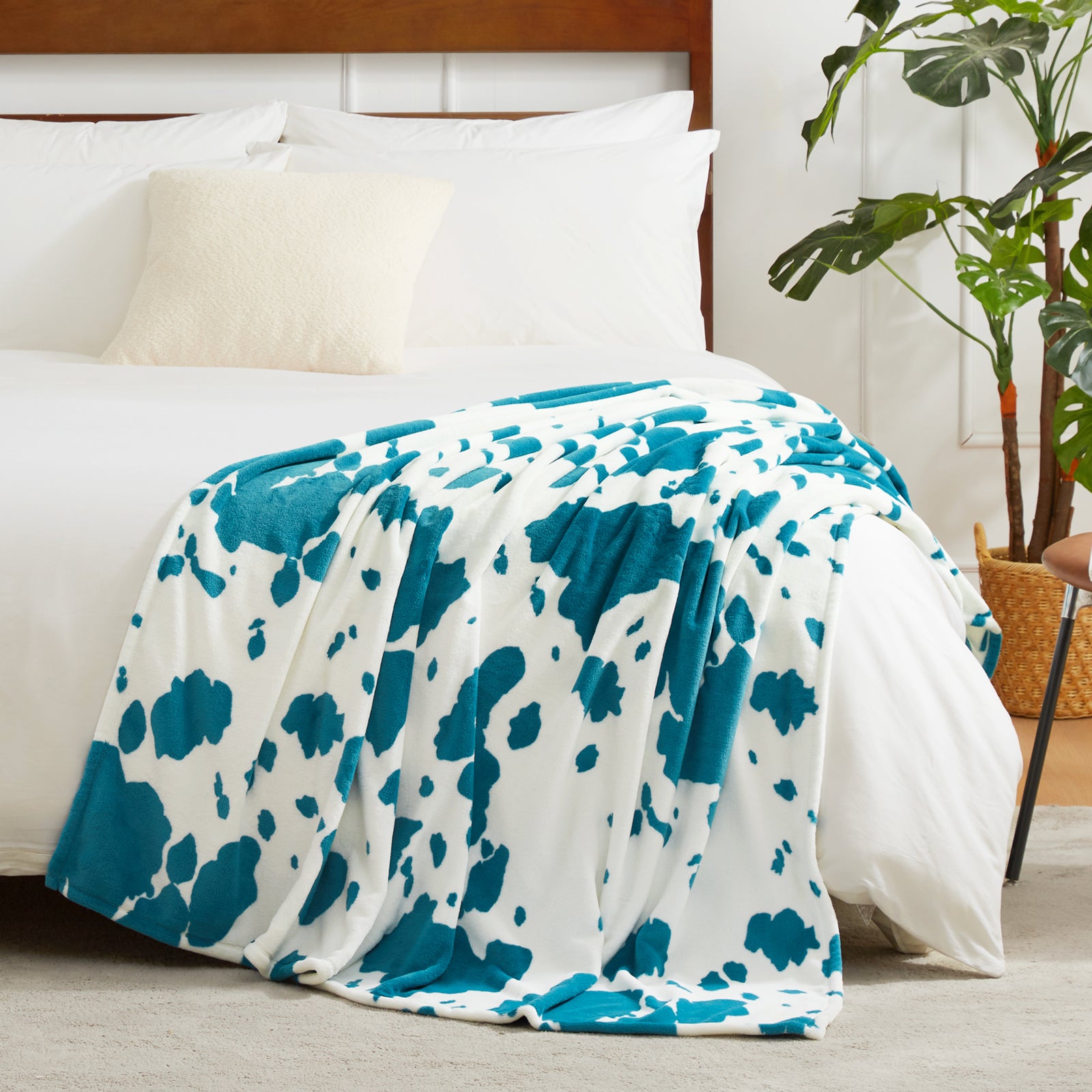 Blue and white patterned blanket on a bed with pillows and a plant in the background  #color_Blue