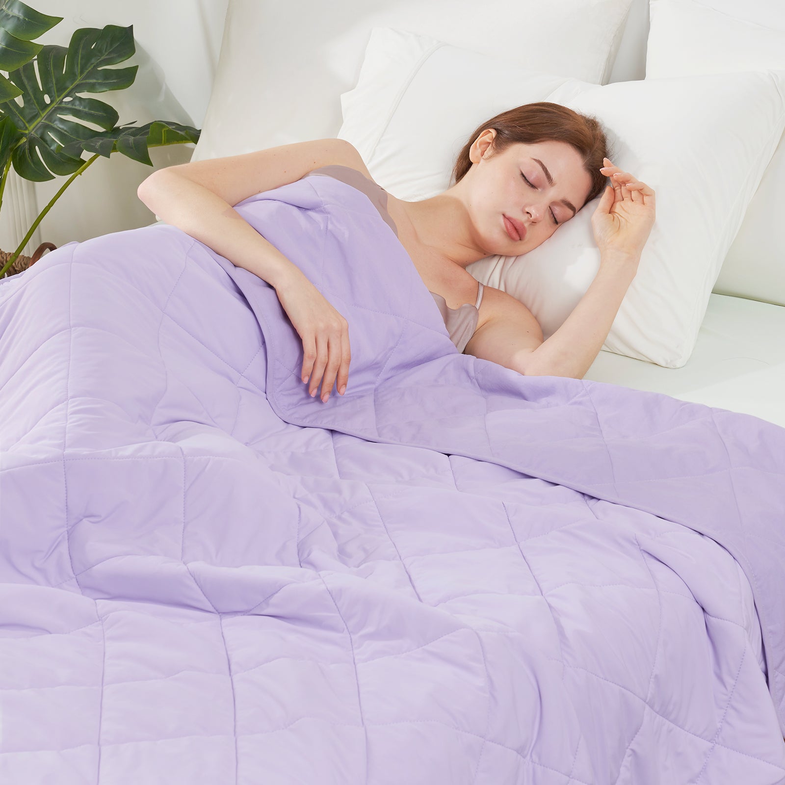 Woman sleeping under a purple comforter in a cozy bedroom setting.   #color_Purple