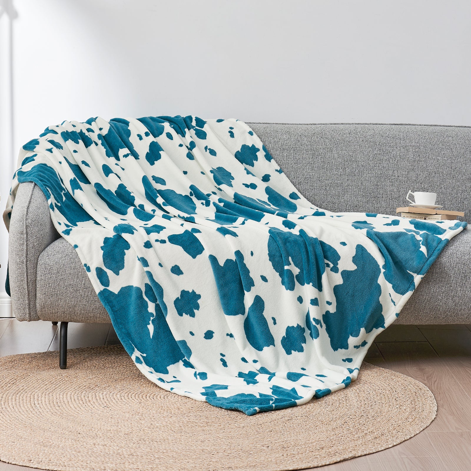 Blue and white patterned throw blanket draped over a gray sofa in a living room setting.#color_Blue