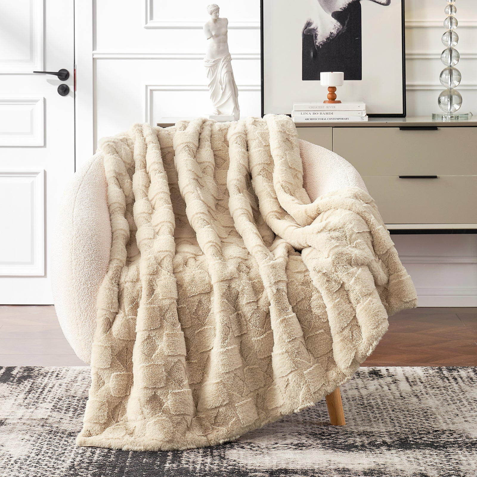 Beige textured blanket draped over a wooden chair in a room with white walls and furniture.#color_Beige