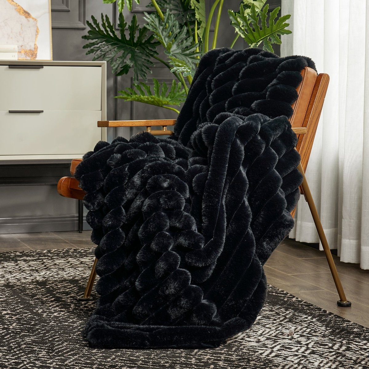 Cozy Bliss Ultra Chunky Striped Faux Fur Throw Blanket in Black layered on an armchair. #color_Black