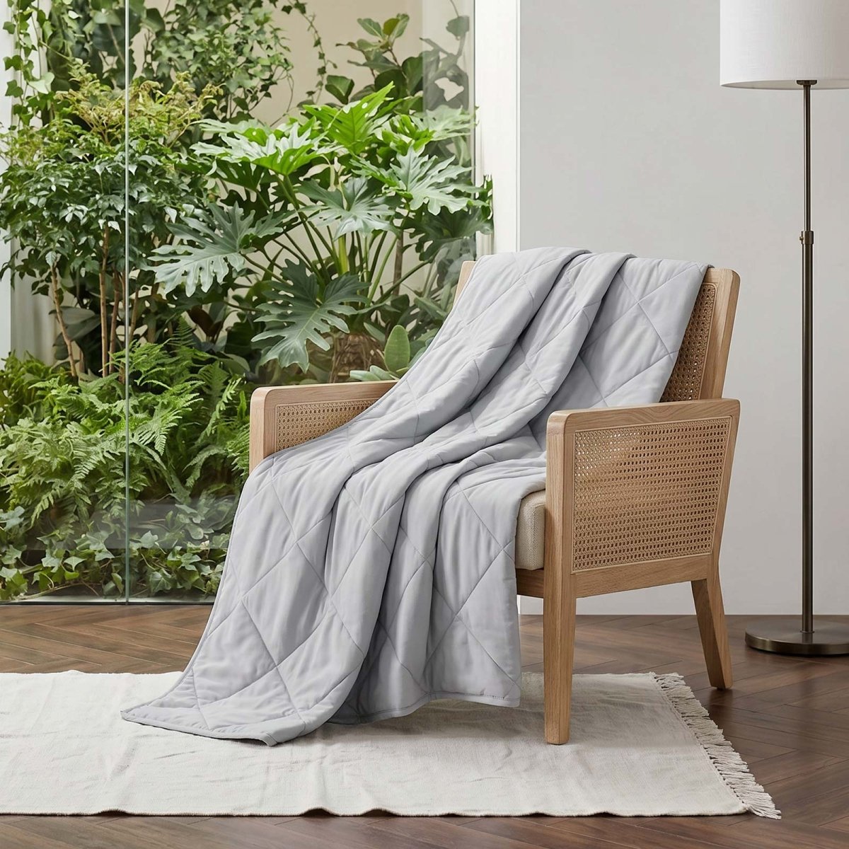 Cozy Bliss Cool grey cooling blanket draped over a beige sofa. #color_Cool Grey