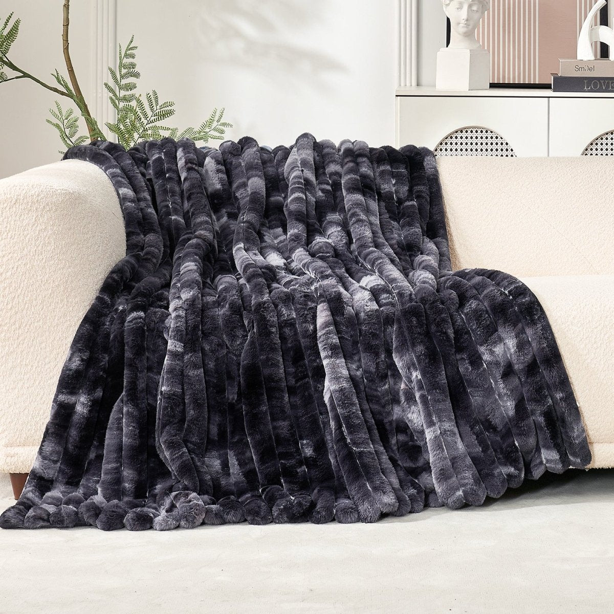 Tie-dye black striped blanket draped over a white sofa in a home setting. #color_Tie-dye Black
