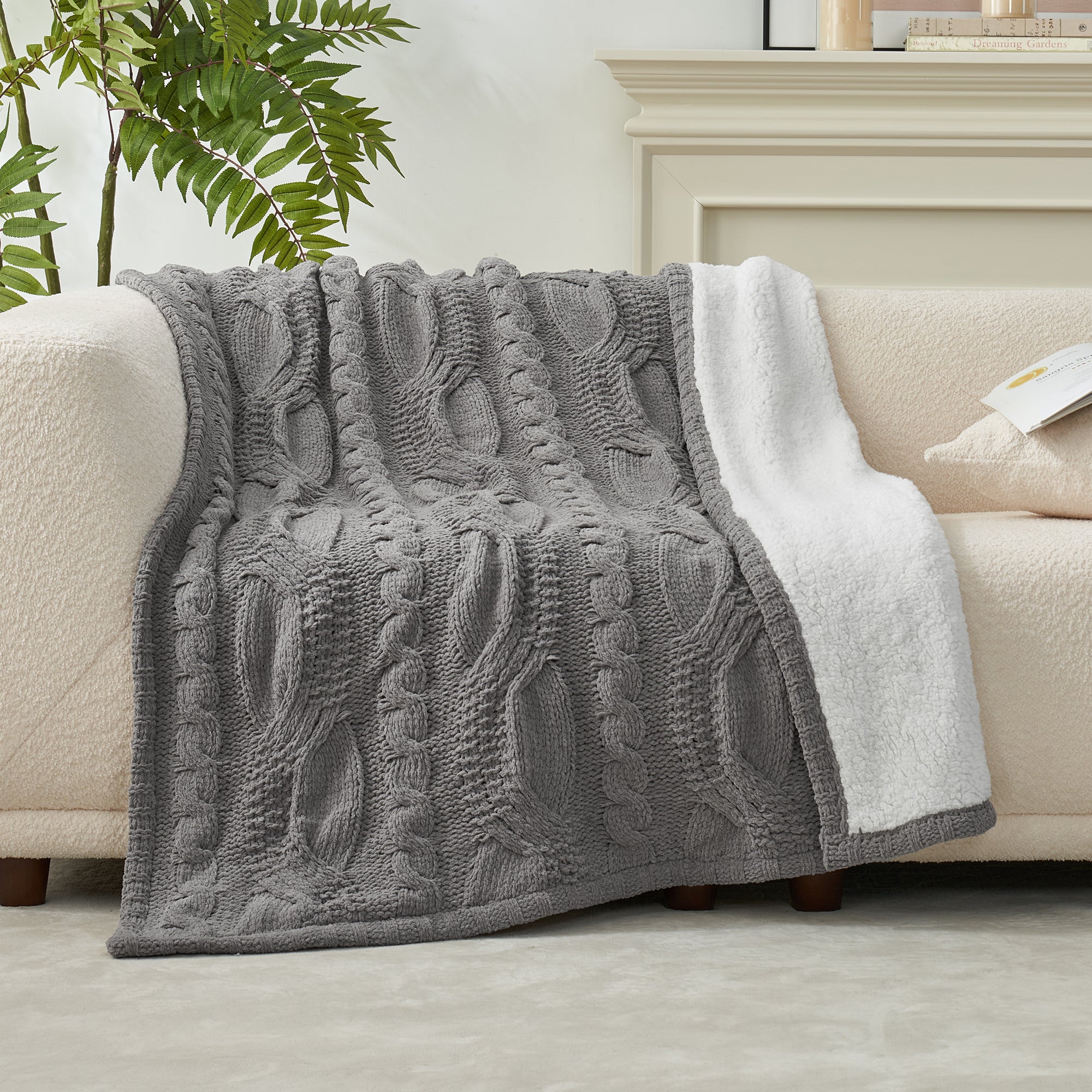 Gray textured blanket draped over a beige sofa with a white pillow. #Color_Grey