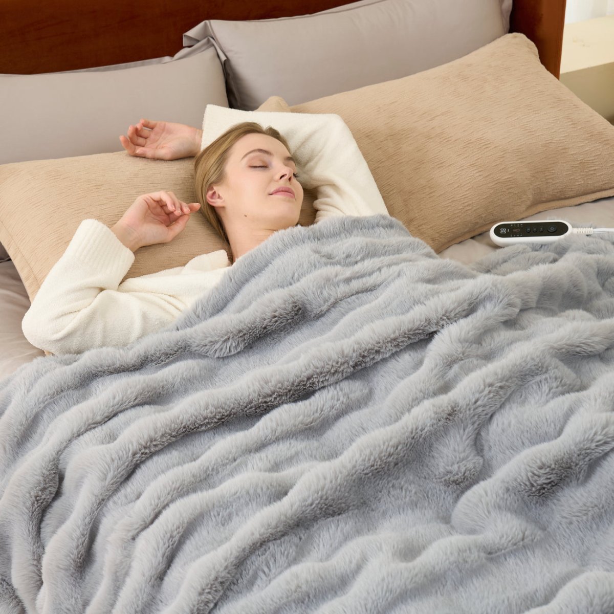 Woman lying in bed under a grey heated electric blanket with a remote control. #color_Light Grey