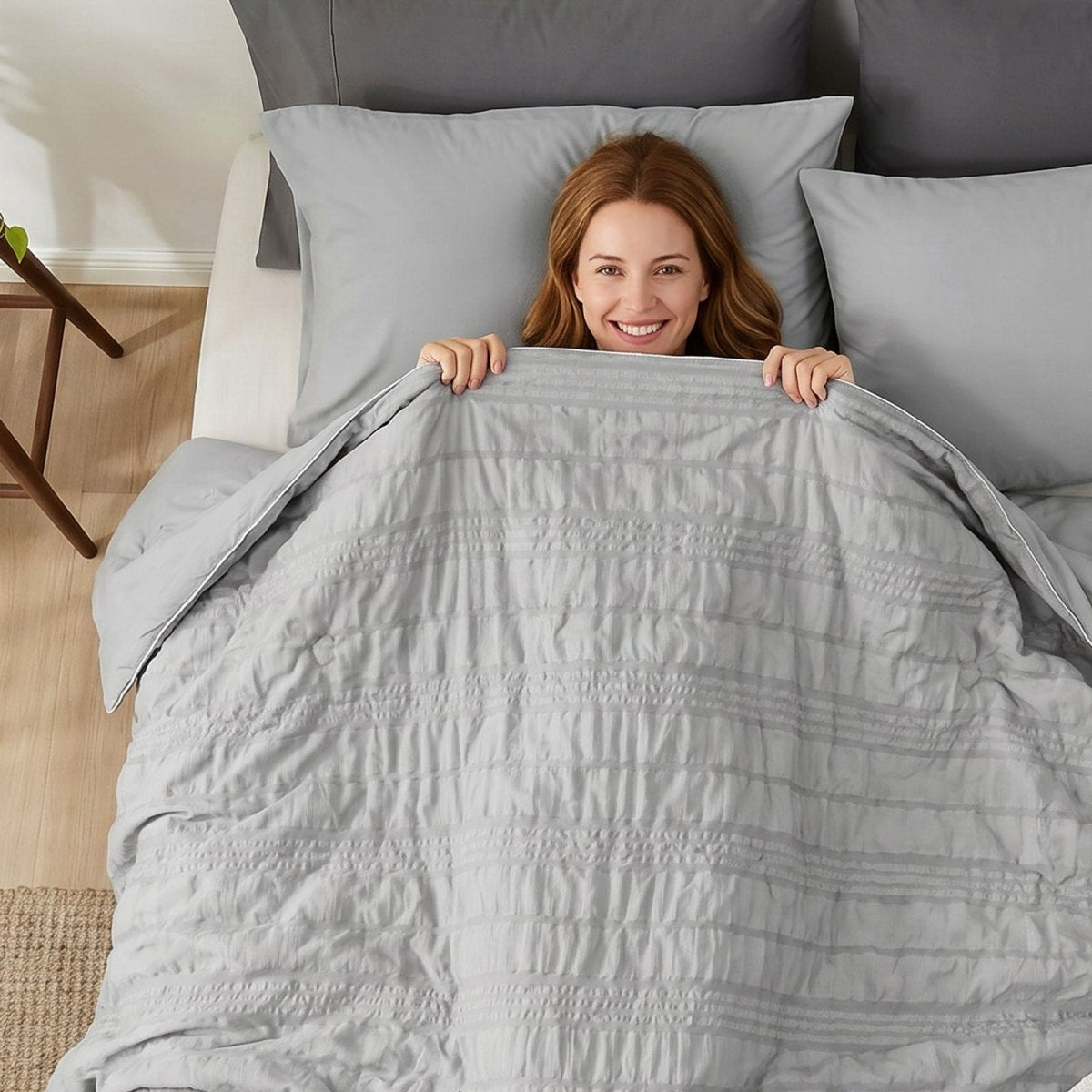 Woman relaxing with Cozy Bliss cooling comforter.#color_Light Grey