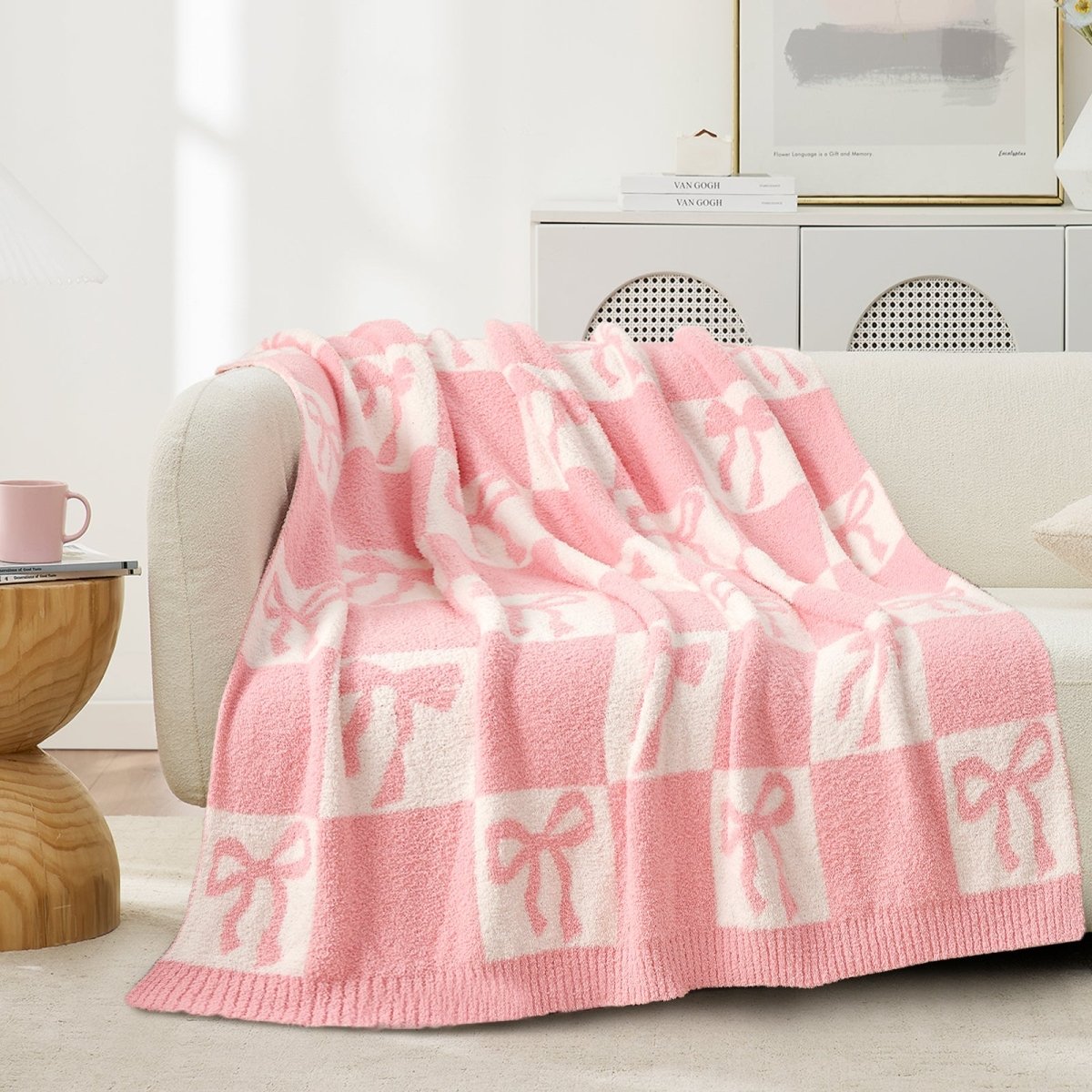 Reversible Checkered Bow Feather Yarn Throw Blanket in Pink draped over a sofa, showcasing soft feather yarn texture and bow checkered pattern design. #color_Pink