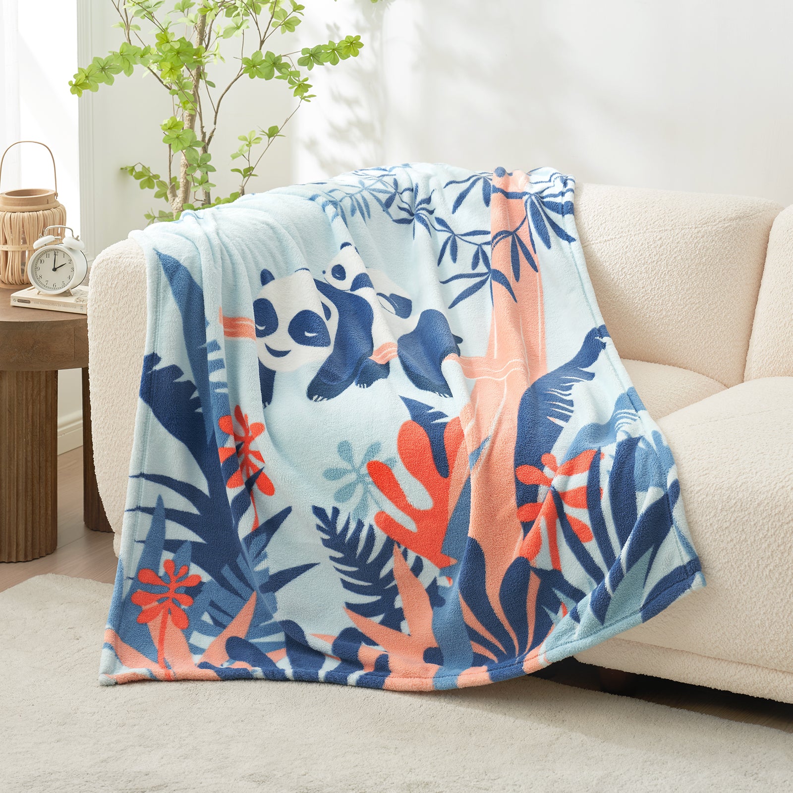 Floral and panda-patterned blanket draped over a couch in a living room setting. #color_Panda Adventure