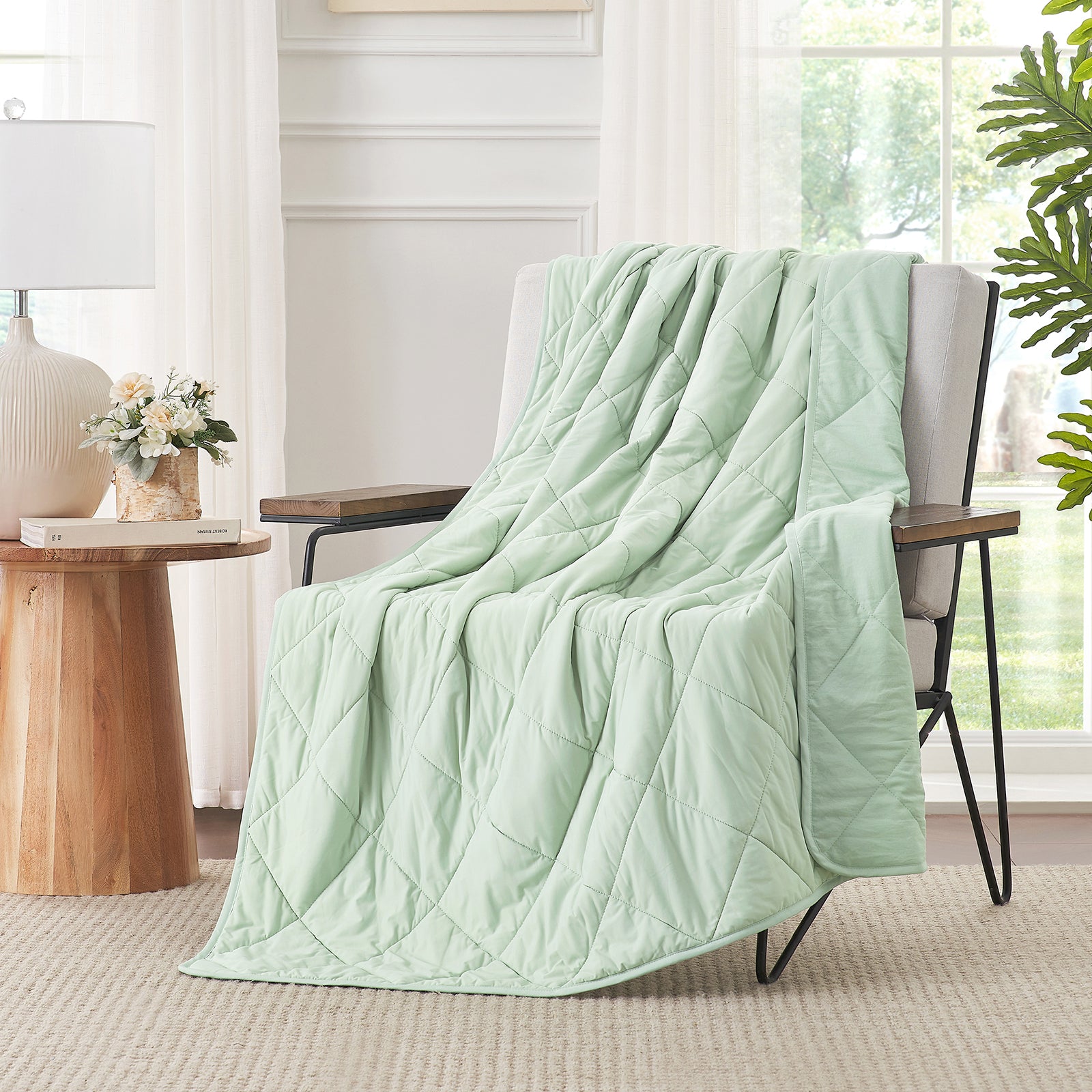 Light green quilt draped over a chair in a bright room with natural light.  #color_Mint Green