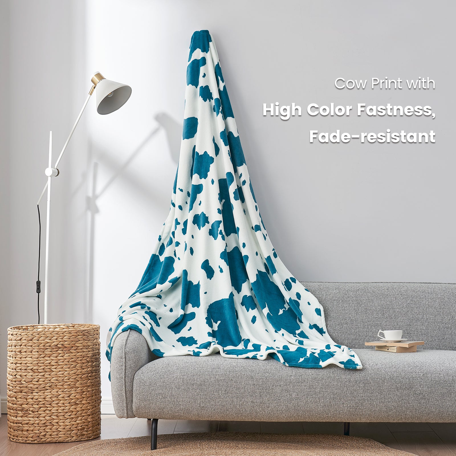 Cow print blanket draped over a sofa with text about color fastness and fade resistance.  #color_Blue