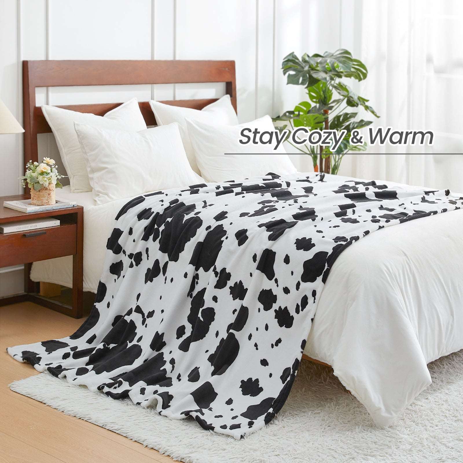 Cozy Bliss cow print blanket on bed. Stay Cozy & Warm #color_Black White