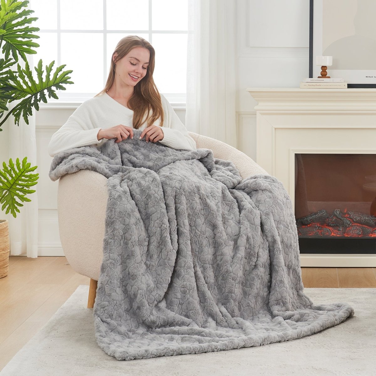 Woman holding a grey blanket in a cozy living room with a fireplace. #color_Grey