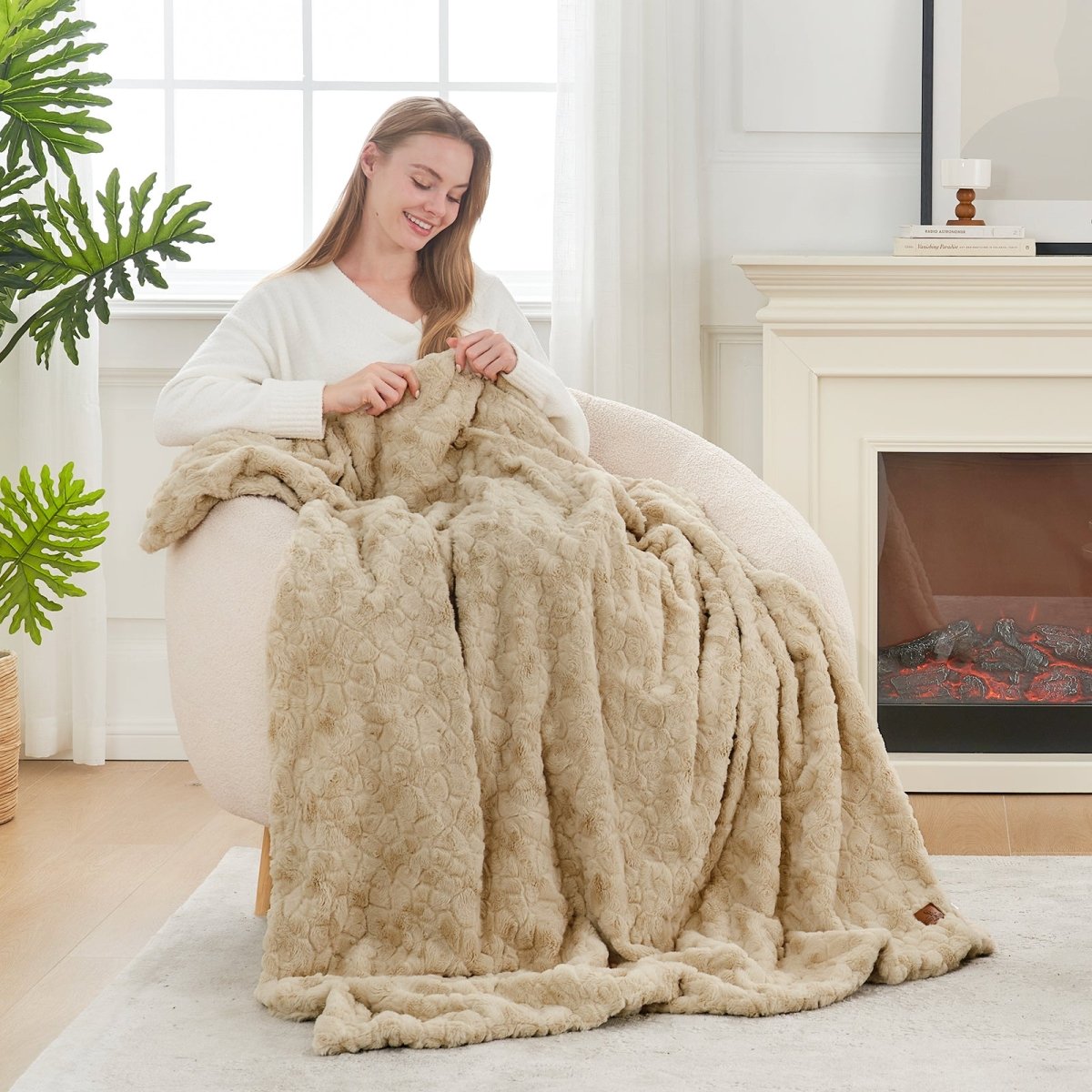 Woman holding a beige blanket in a cozy living room with a fireplace. #color_Khaki