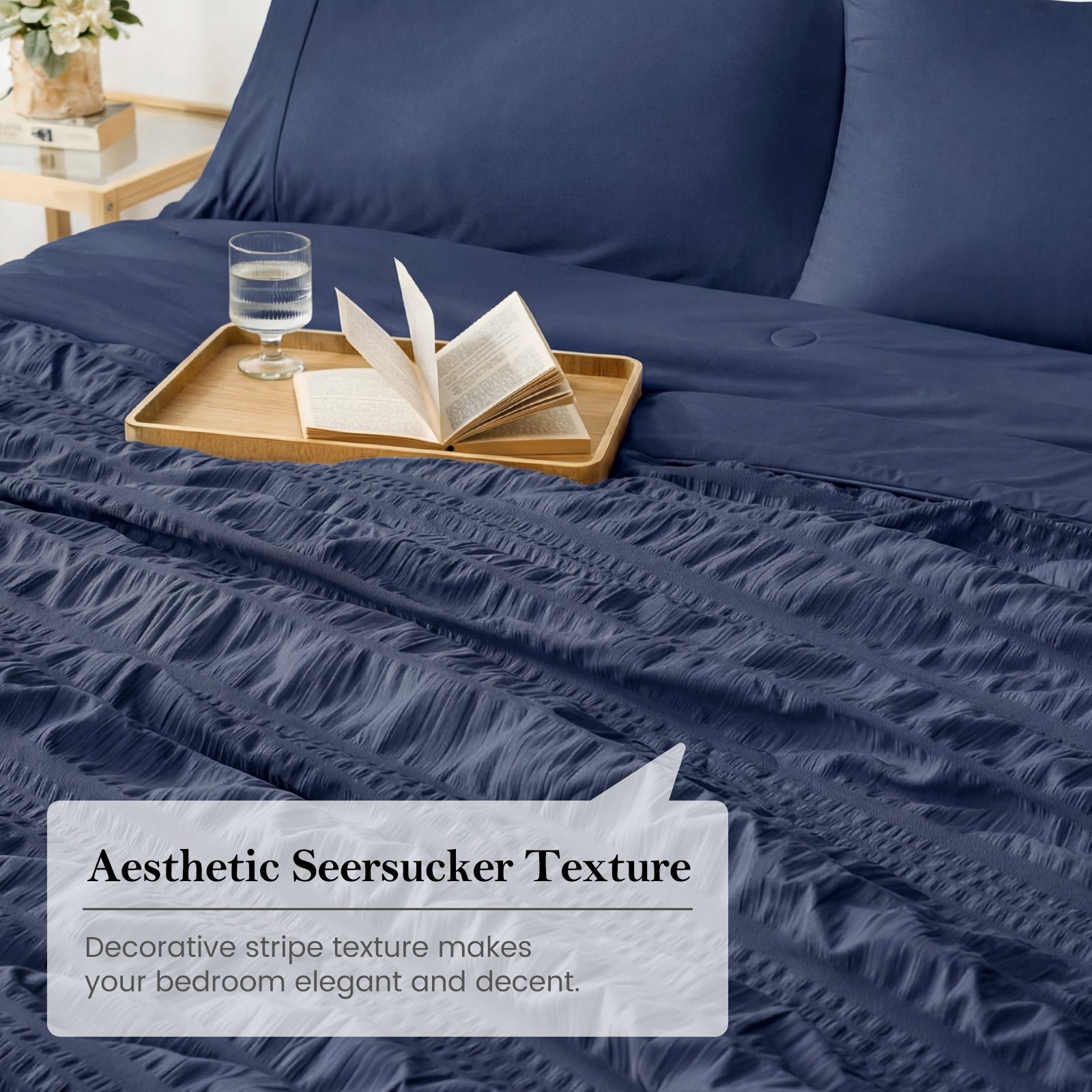Navy blue seersucker cooling comforter on bed with tray and book, soft breathable textured bedding in a cozy bedroom setting#color_Navy Blue