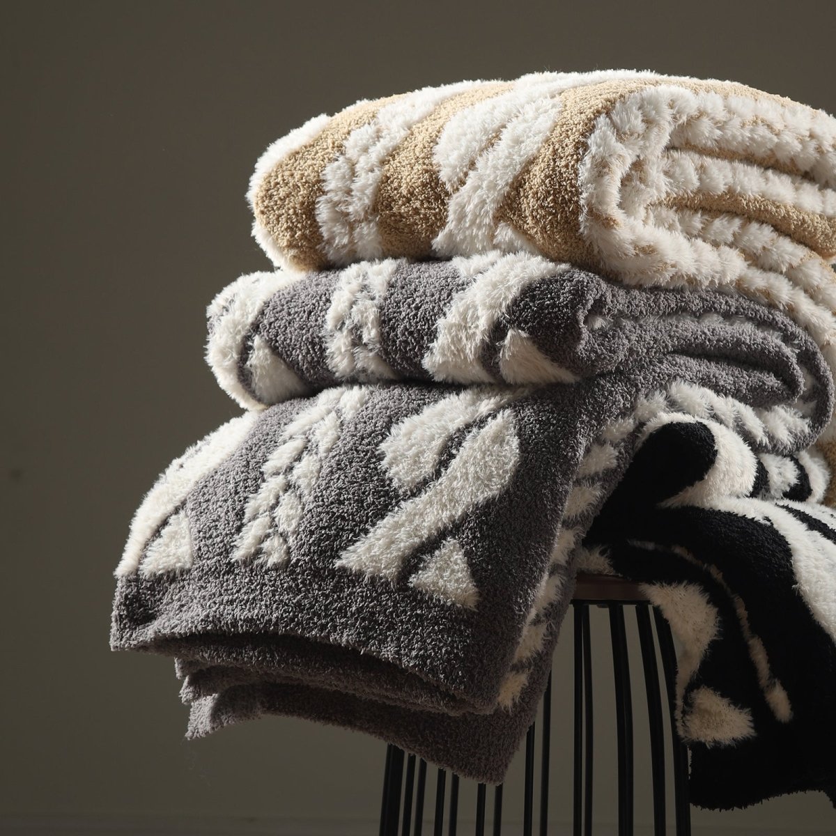 Faux Mink Cable Knit Throw Blanket neatly stacked on a stool, highlighting soft texture and layered premium look. #color_Black