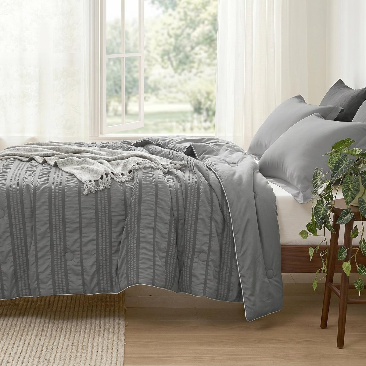 Cozy Bliss seersucker cooling comforter on bed in side view.#color_Dark Grey