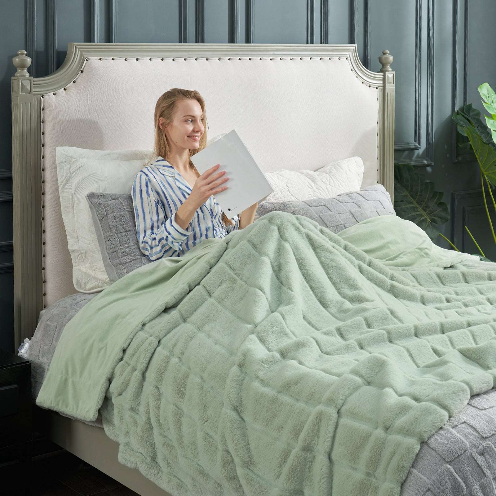 Woman reading with Cozy Bliss green fuzzy blanket on bed  #color_Sage Green