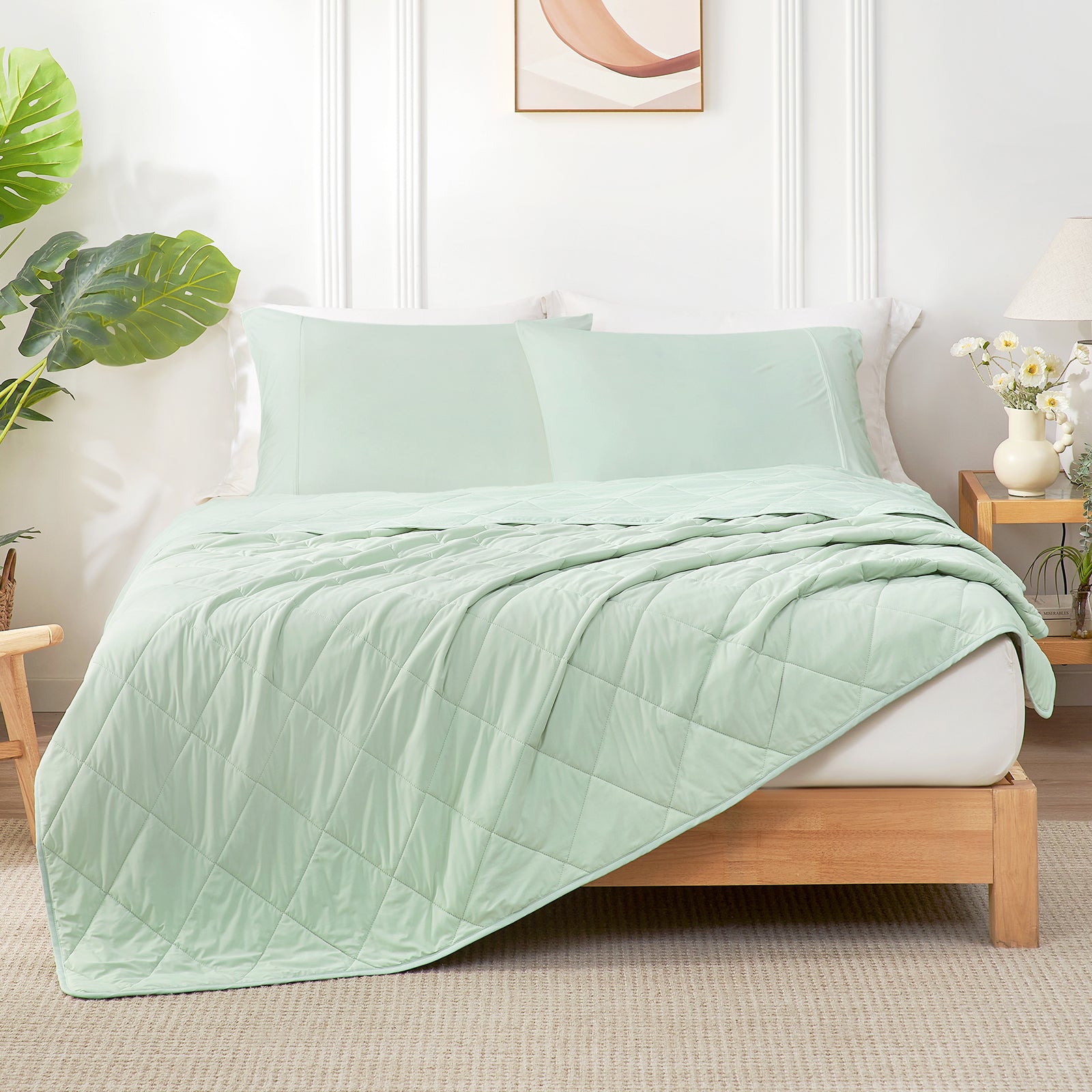 Light green quilt and pillow on a bed in a bedroom with plants and decor.  #color_Mint Green