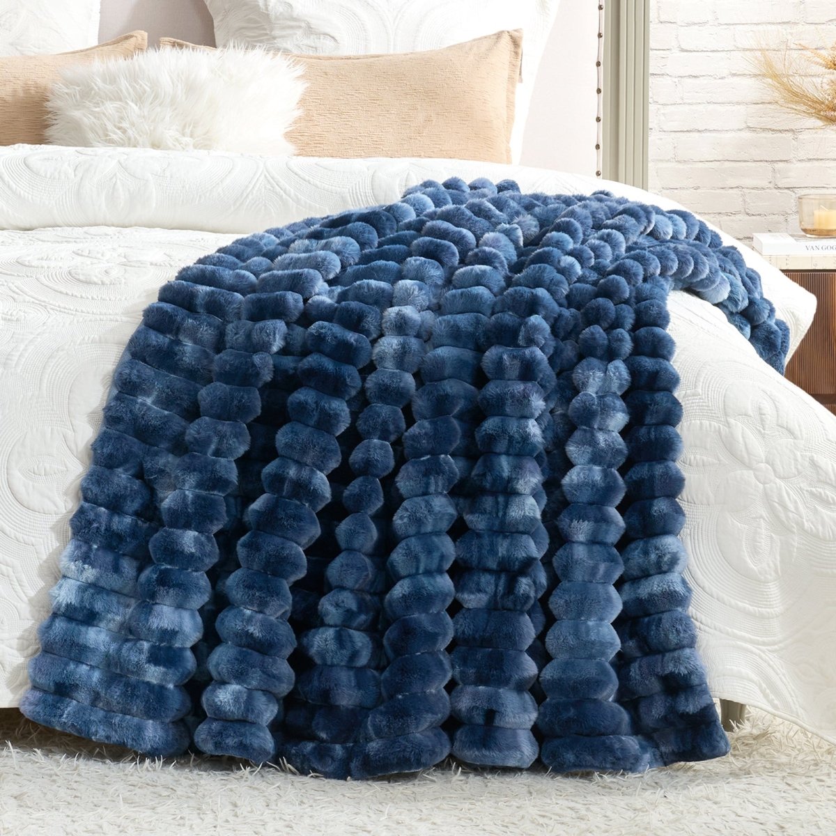 Blue textured blanket draped over a bed with white bedding and pillows. #color_Tie-dye Blue