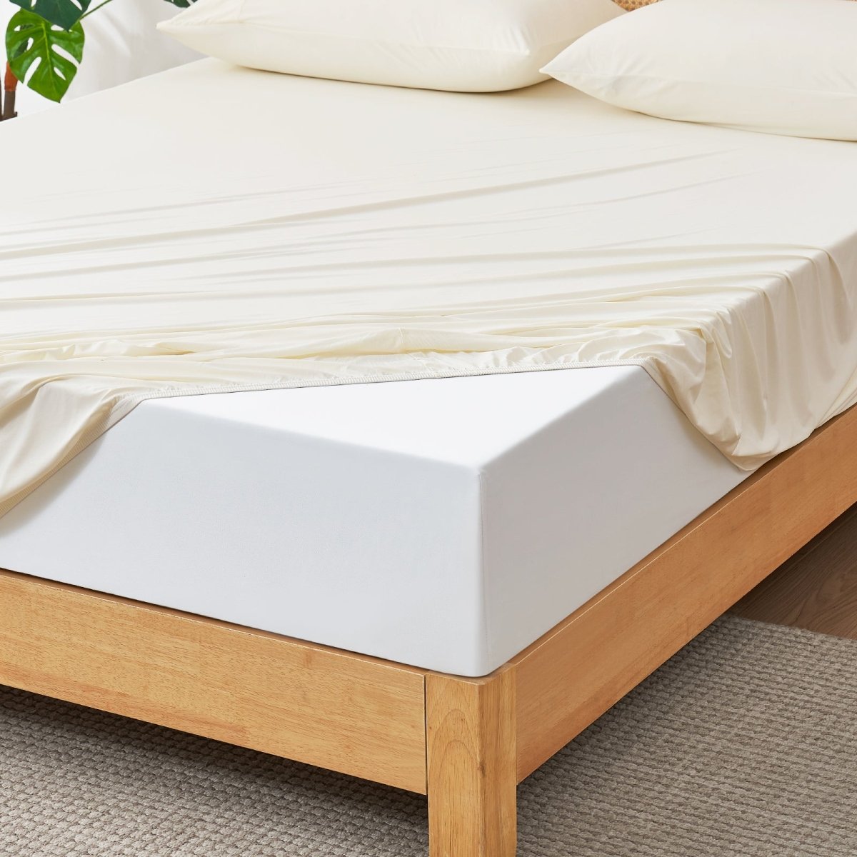 Wooden bed frame with a white mattress and beige bedding on a carpeted floor. #Color_Cream White