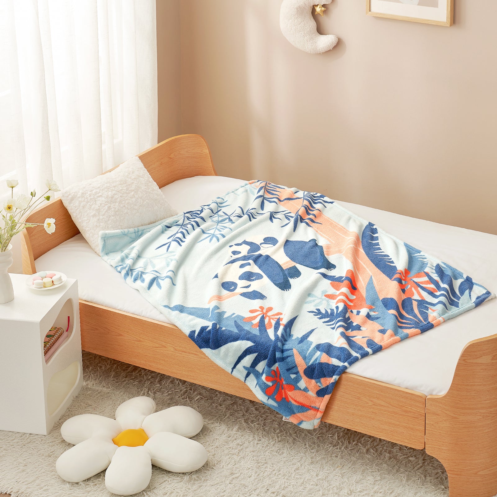 Bed with a colorful blanket featuring animals, next to a nightstand with a small plant. #color_Panda Adventure
