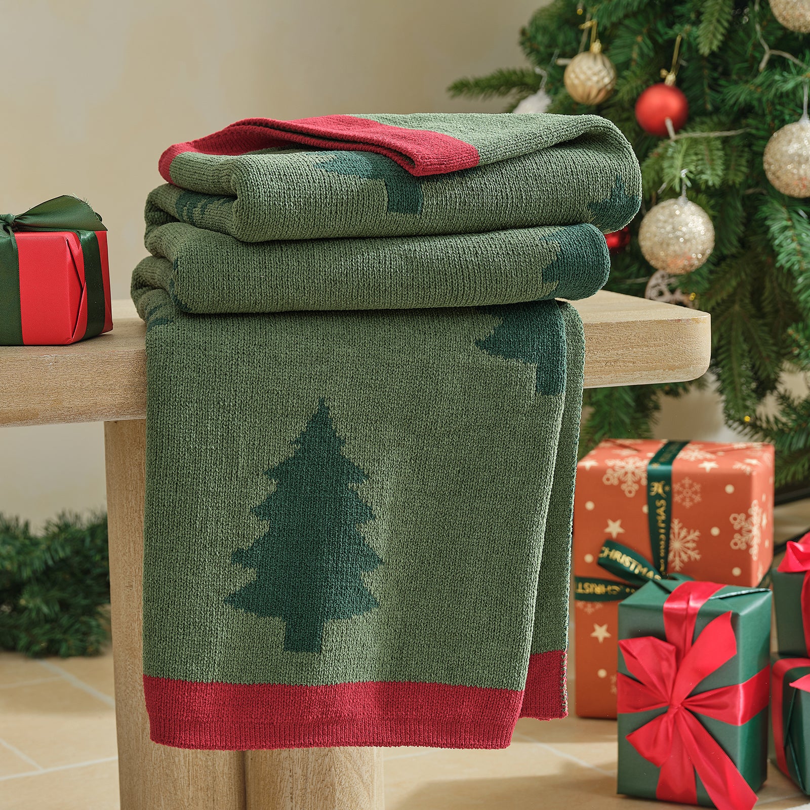 Green blanket with tree design on a wooden surface, surrounded by Christmas presents and decorations. #color_Christmas Tree