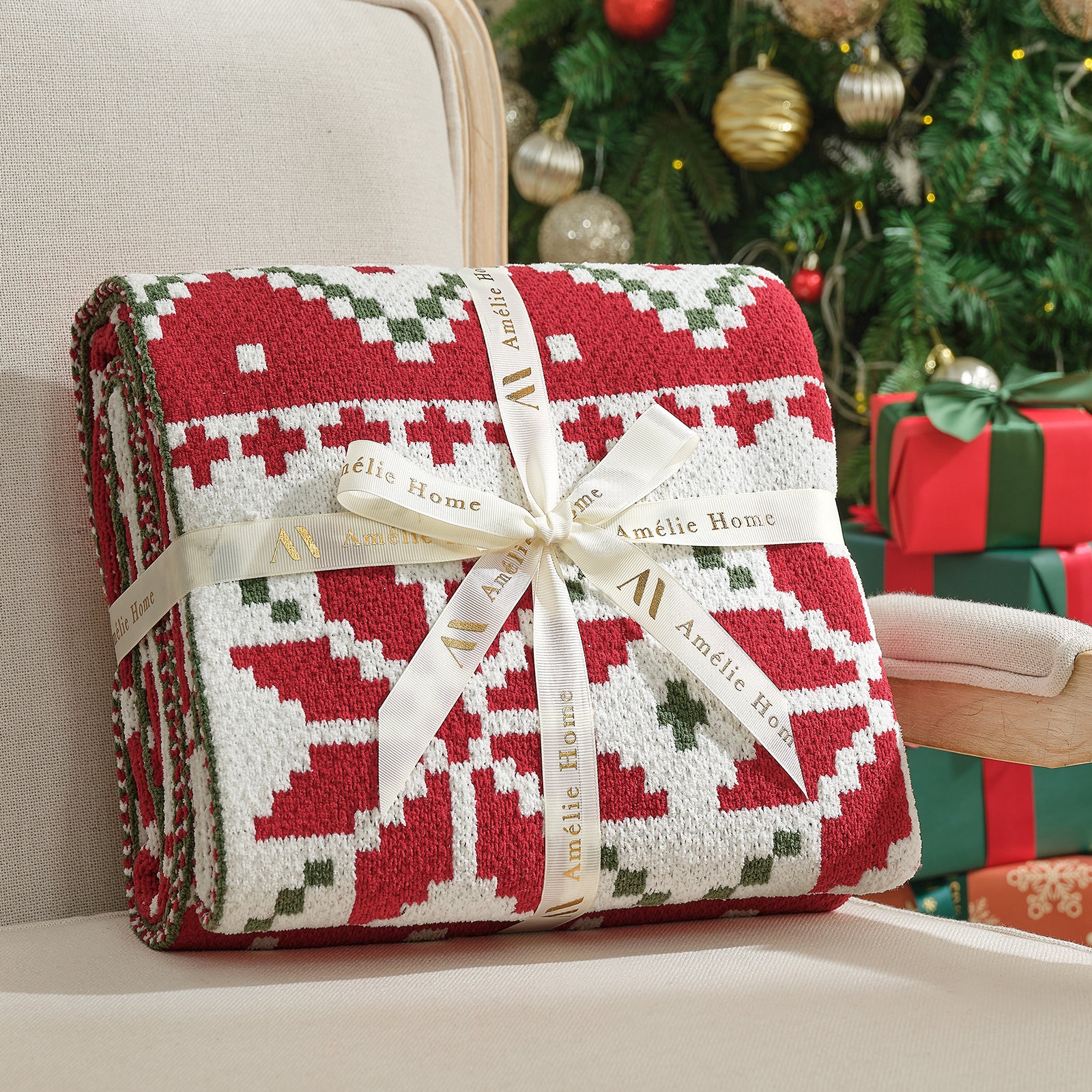 Red and white patterned blanket with a bow, branded 'Amelie Home', against a festive background with Christmas tree and presents. #color_Fair Isle