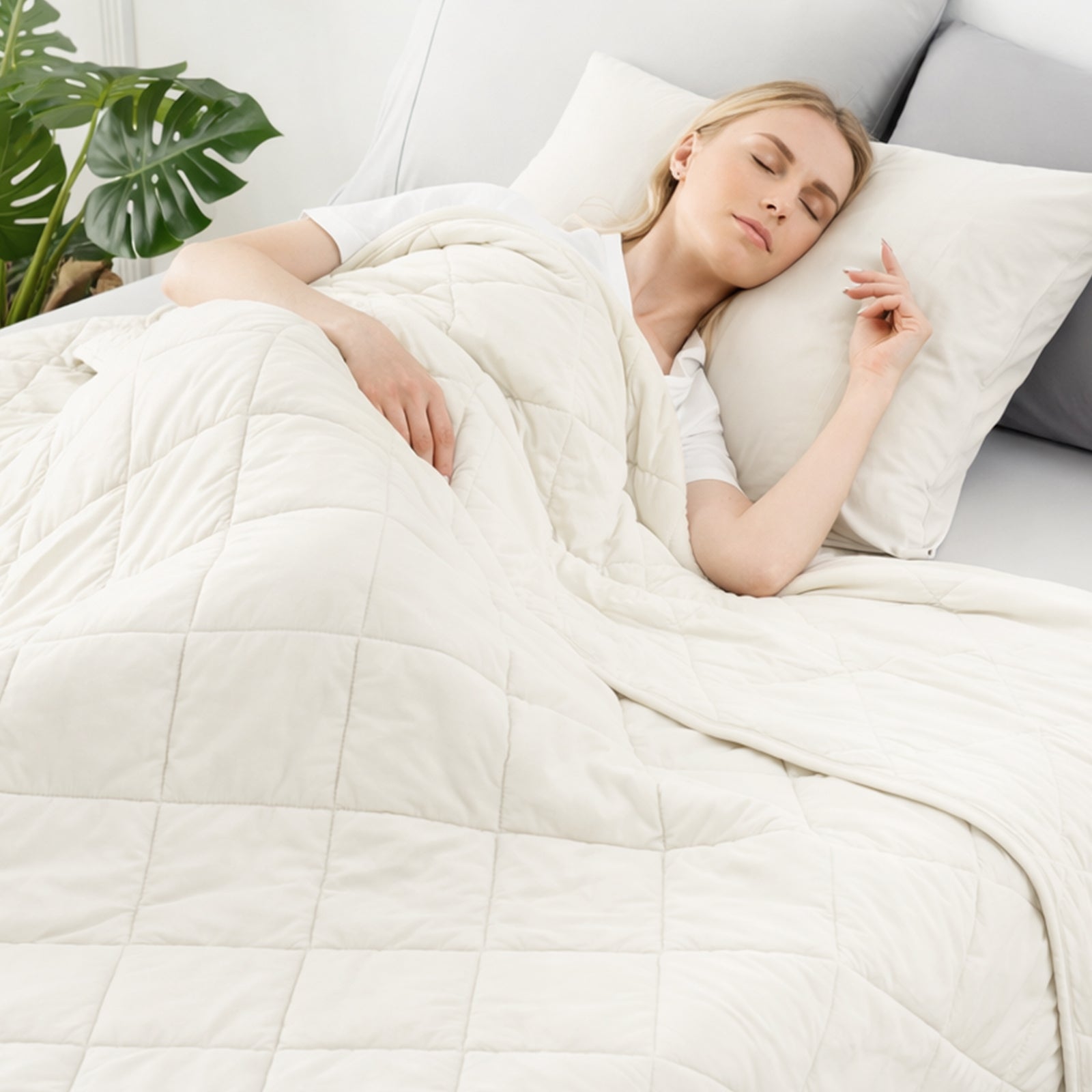 Woman sleeping under a white comforter in a cozy bedroom setting.   #color_White