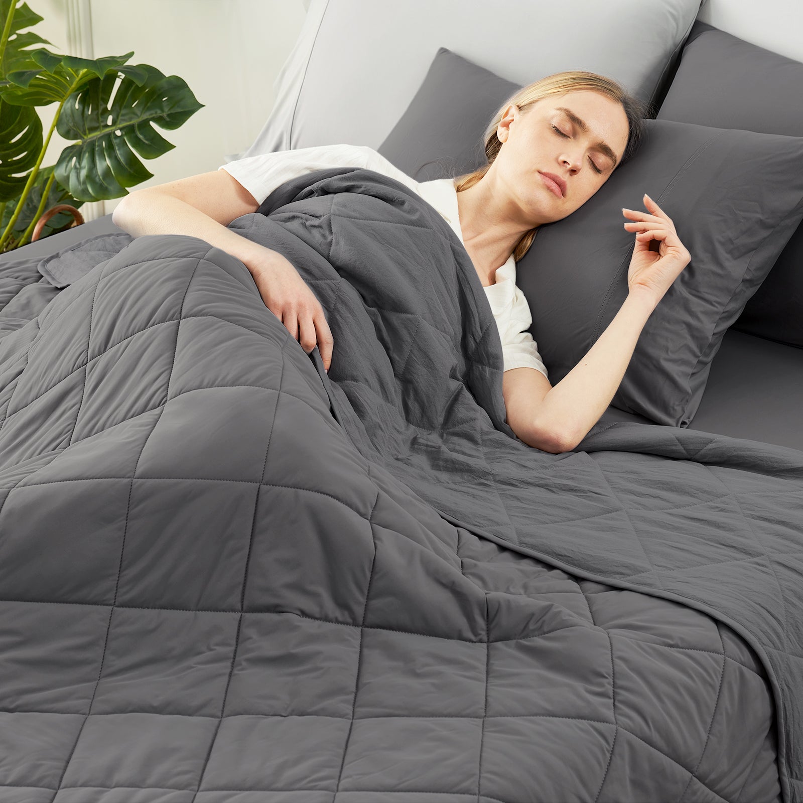 Woman sleeping under a charcoal grey comforter in a cozy bedroom setting.   #color_Charcoal Grey