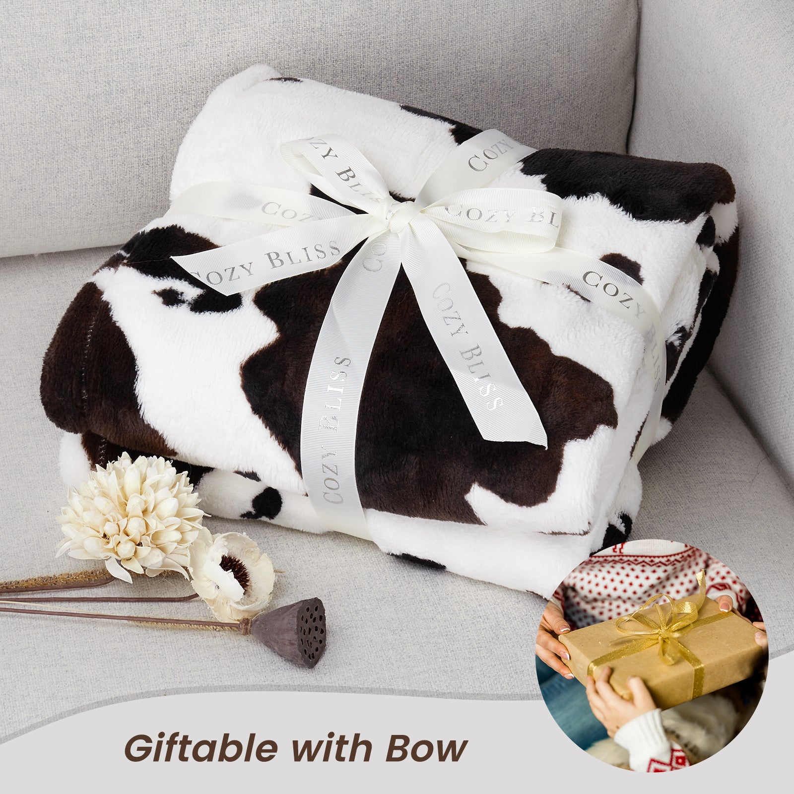 Cow print blanket with a bow on a gray surface, accompanied by decorative elements. #color_Black Brown