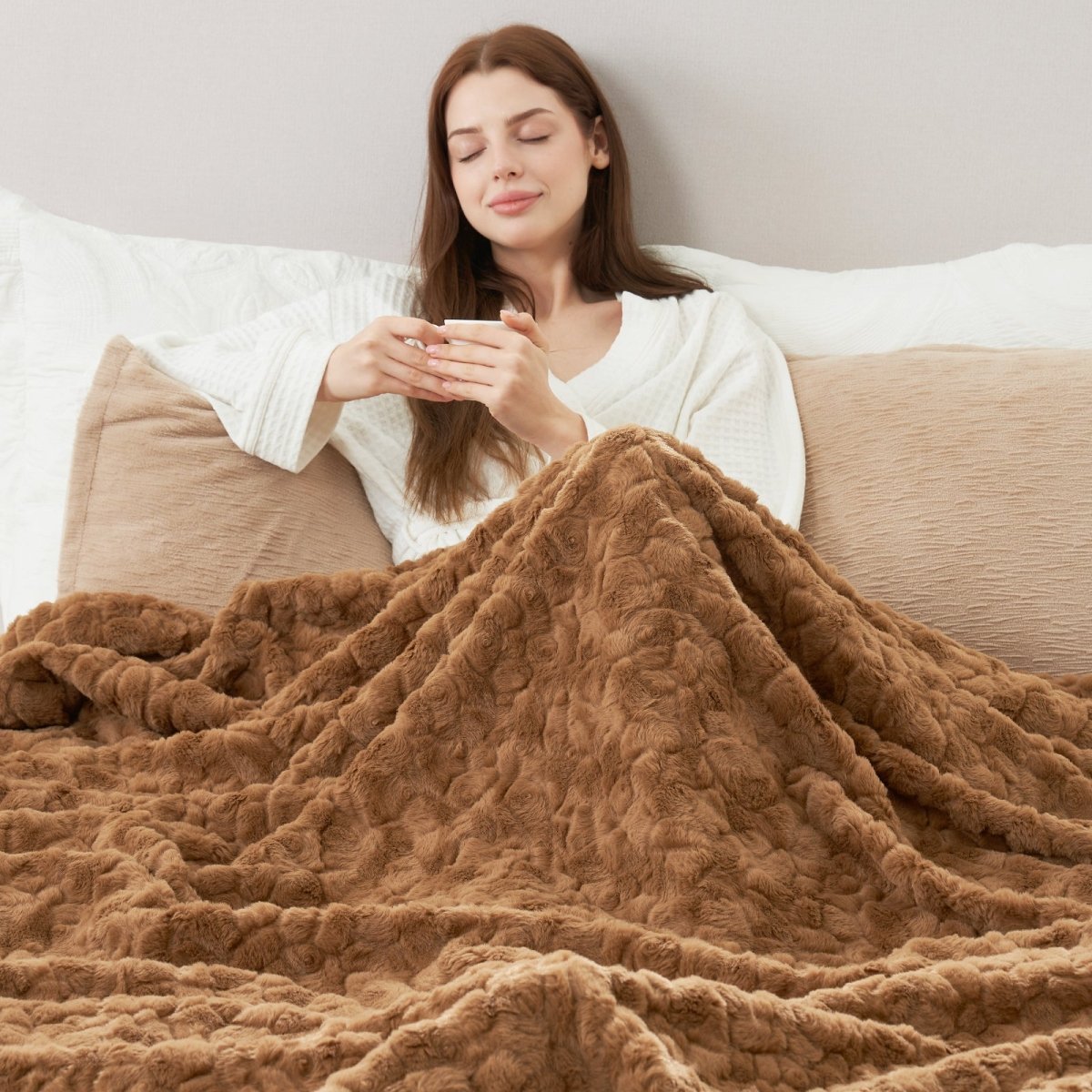 Woman wrapped in a brown blanket on a couch, holding a cup. #color_Brown