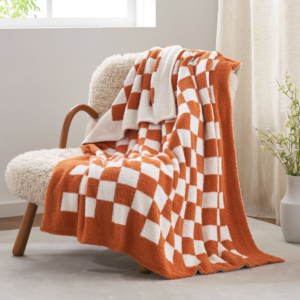 Checkered Feather Yarn Knit Throw Blanket in Burnt Orange front view draped over a chair, showcasing soft texture and checkered pattern design. #Color_Burnt Orange