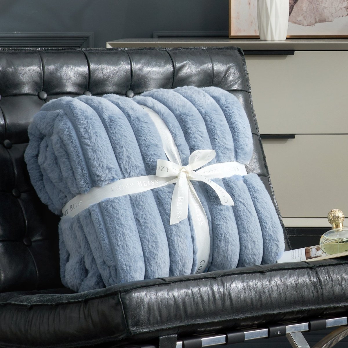 Fluffy blue striped faux fur throw blanket with a bow on a sofa. #color_Misty Blue