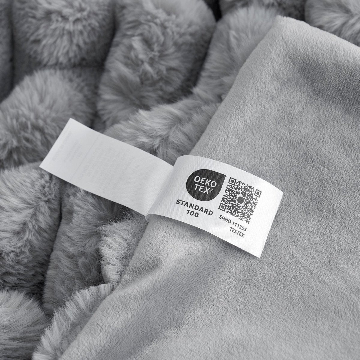 Close-up of Grey Cozy Bliss faux fur blanket Oeko-Tex certified label. #color_Grey