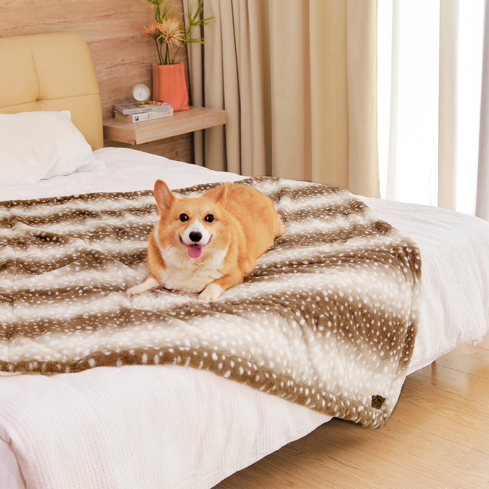 Dog sitting on a cozy bliss leakproof faux fur pet blanket on a bed, smiling. #color_Brown Sherpa Deer