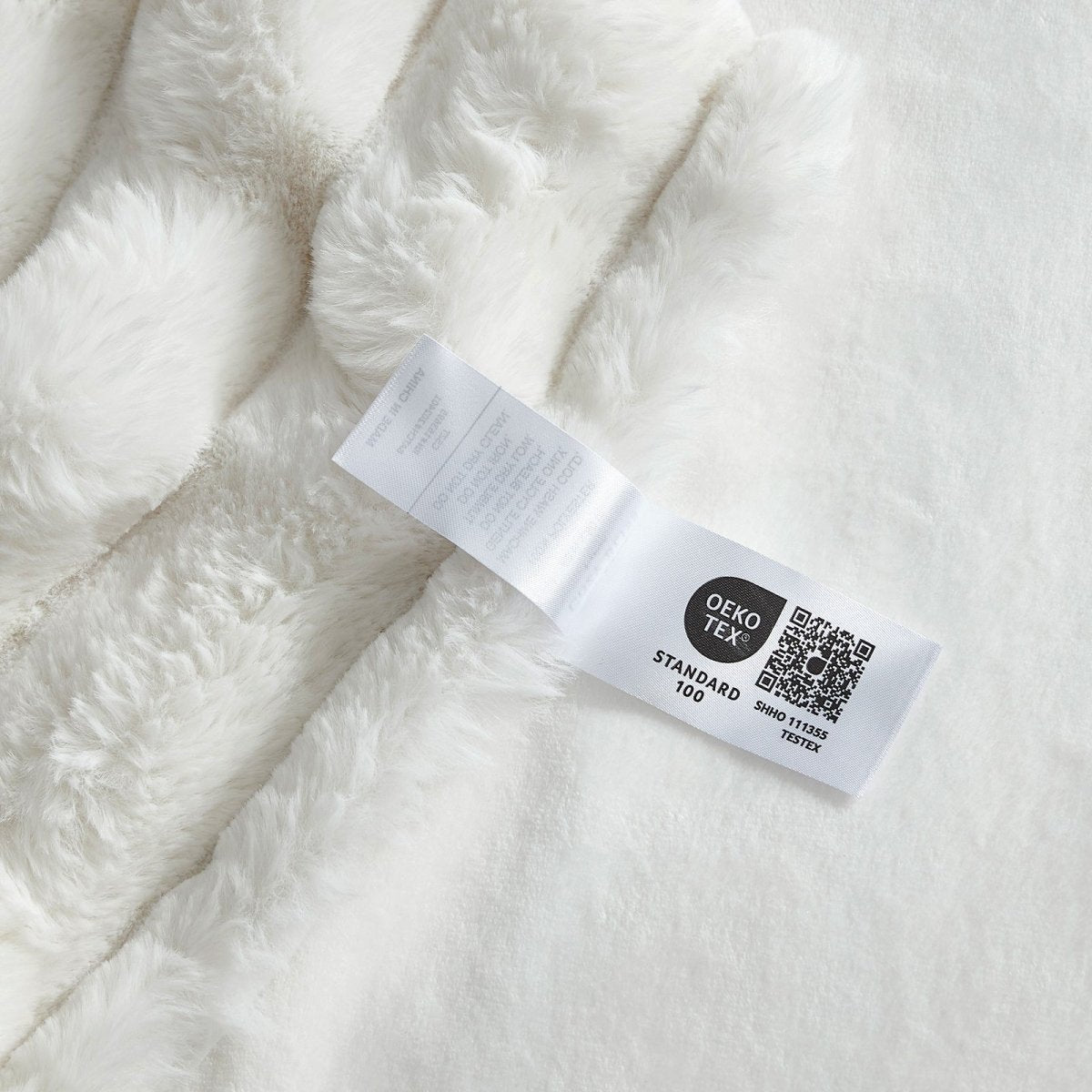 Close-up of OEKO-TEX certified label of  Cozy Bliss faux fur blanket  #color_Cream White